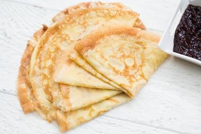 Perfect Crepes on a table with a bowl of jam besides it