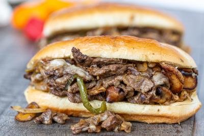 Philly Cheesesteak Sandwich on a tray with another sandwich in background