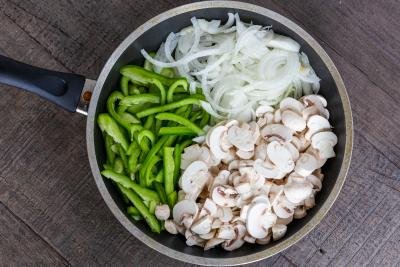 skillet with mushrooms, bell peppers and onions