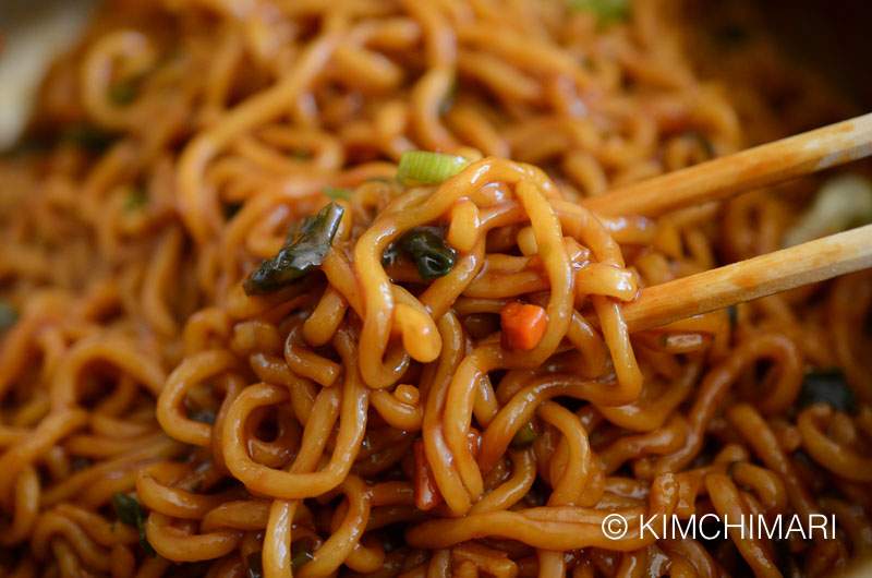 closeup of ram-don jjapaguri noodles picked up with chopsticks - all finished in pot