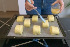 Brushing the gata with egg wash before baking