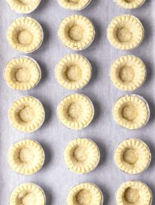Pre-baked tart shells on a baking sheet.