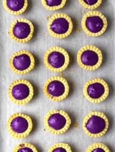 Freshly baked mini ube tarts on a baking pan.
