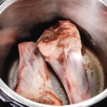 lamb shanks being seared in an instant pot