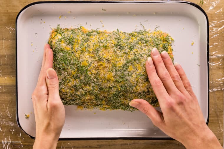 Overhead action photo of a cure being applied to a raw slab of salmon.