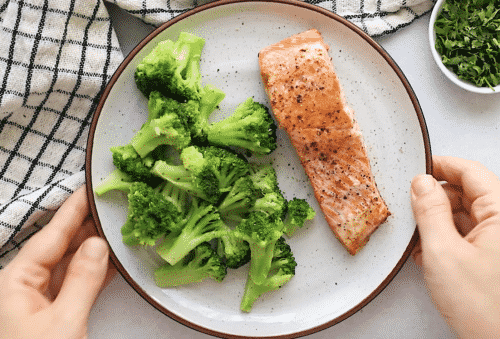 salmon on a white plate containing salmon and broccoli