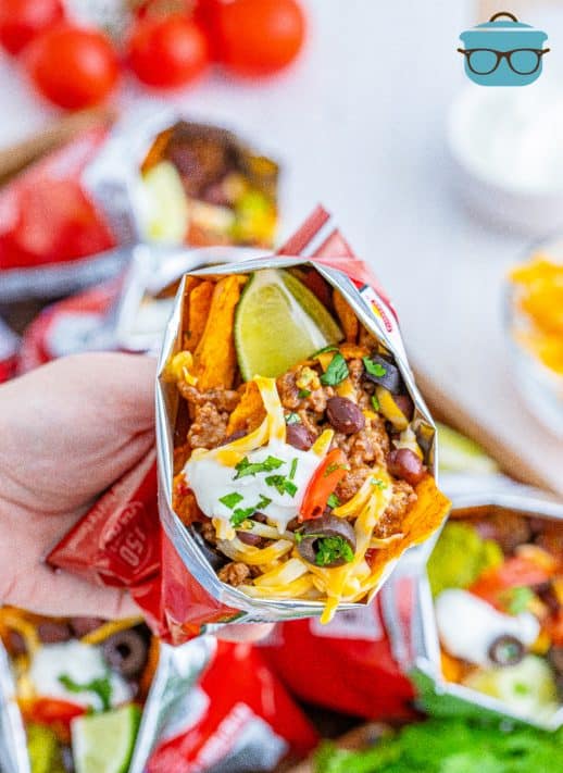 Hand holding one bag of Doritos Walking Tacos showing the inside ingredients