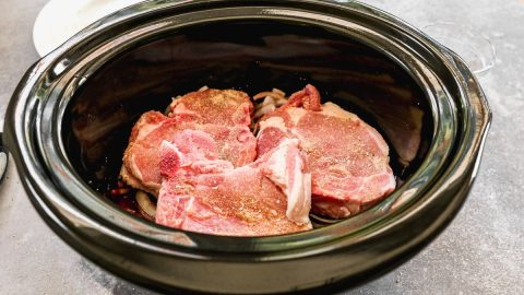 three thick pork chops with the bone in a crockpot